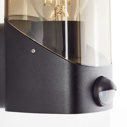 Brilliant - Utomhus vägglampa med sensor MINOU 1xE27/10W/230V IP44 svart/rökig